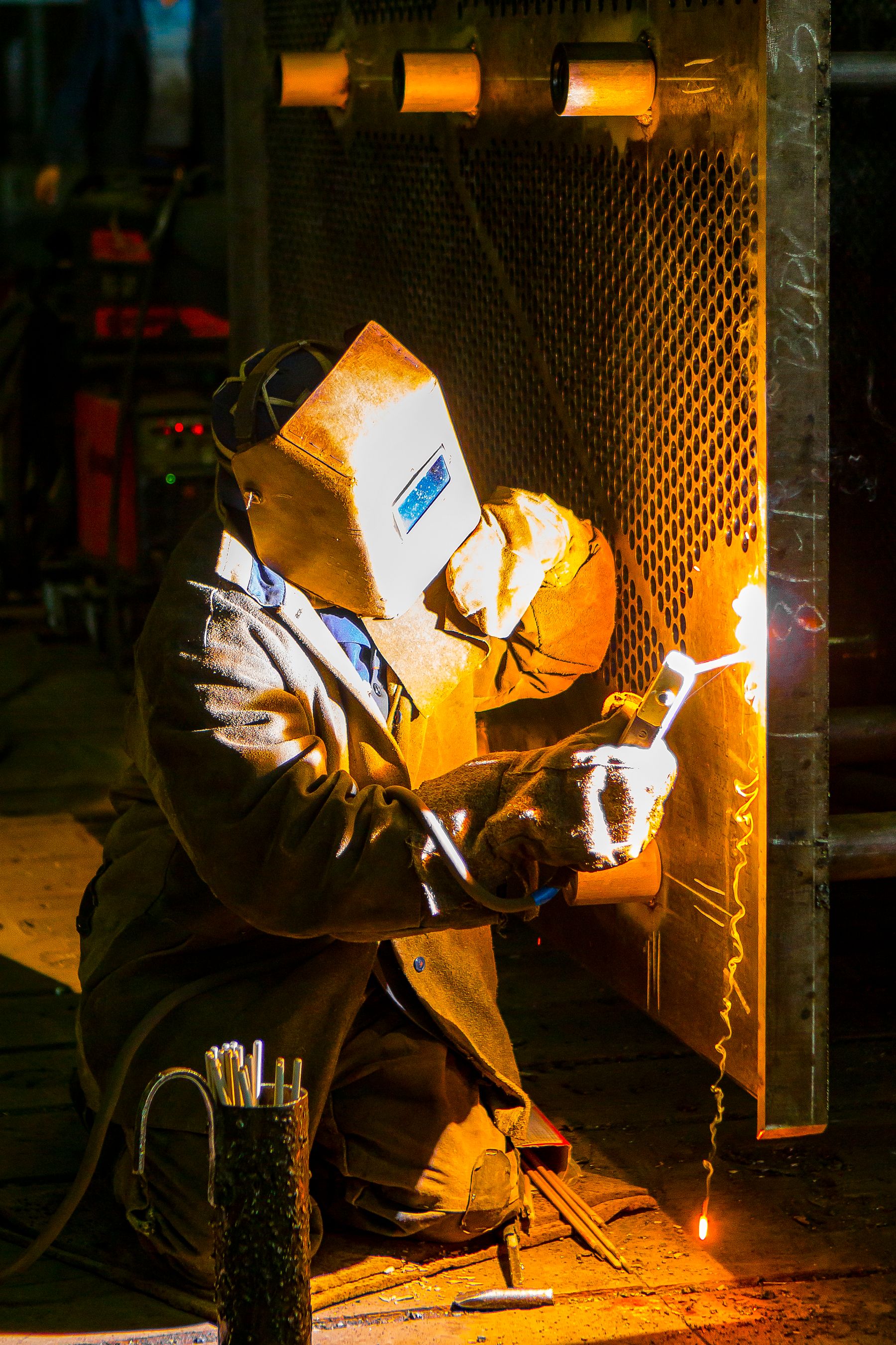 Lasser met laskap werkt aan een metalen werkstuk.