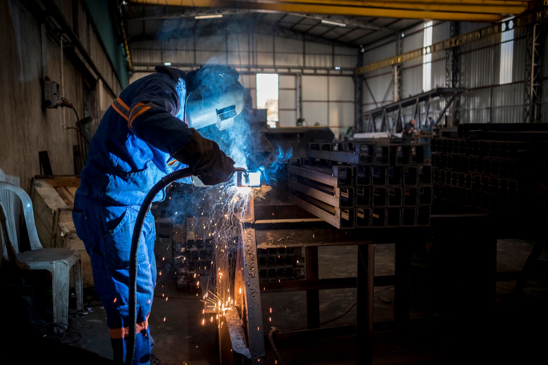 Lasser met beschermende kleding aan het werk in een werkplaats.